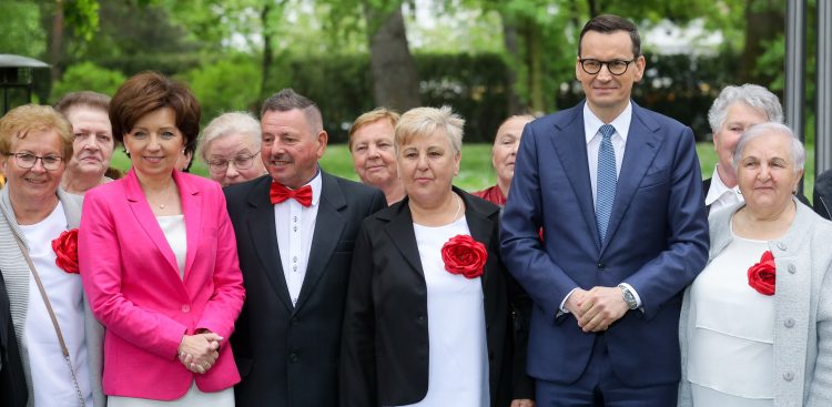 Premier Mateusz Morawiecki i minister rodziny i polityki społecznej Marlena Maląg pozują do pamiątkowego zdjęcia z seniorami, po konferencji prasowej po posiedzeniu rządu (Fot. PAP/Paweł Supernak)