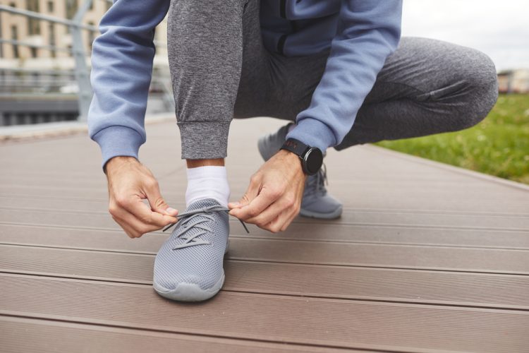 Close-up of athlete tying his sneakers before jogging outdoors
