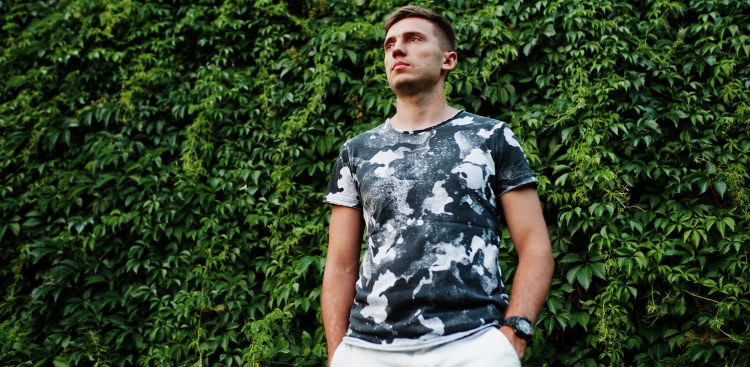 Lifestyle portrait of handsome man posing against greenery wall.