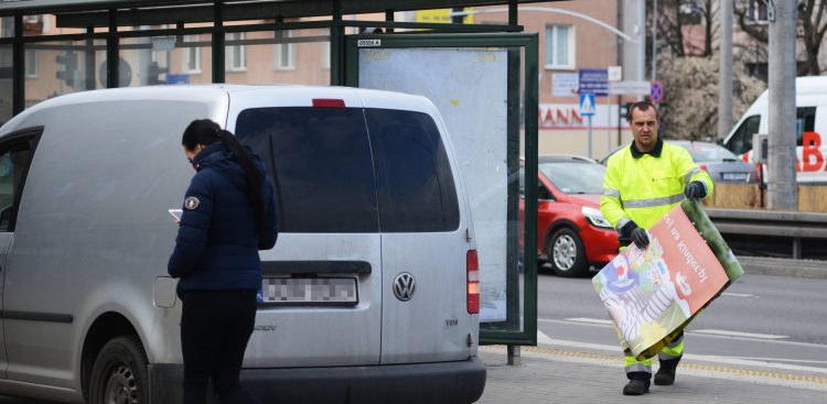 Zdjęcie archiwalne. Wymiana reklamy w gablocie na przystanku komunikacji miejskiej (fot. Andrzej J. Gojke / KFP)