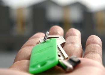 Otwarta dłoń trzymająca klucze z zielonym brelokiem na tle rozmytych budynków mieszkalnych. W Pruszczu Gdańskim przy ul. Skierki powstanie budynek komunalny. Będą w nim 24 mieszkania