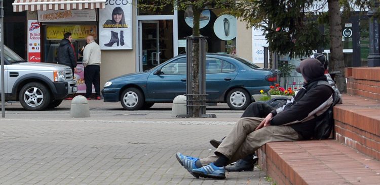 Zdjęcie archiwalne. Gdynia, plac przed kościołem NMP Królowej Polski w Gdyni przy ul. Świętojańskiej. Trzech mężczyzn śpi na ceglanym podeście (fot. GAMMA Atelier/KFP)