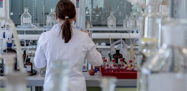 Laboratorium medyczne, kobieta w fartuchu, laborantka odwrócona tyłem, ubrana w fartuch przy naczyniach laboratoryjnych. Medycyna, badania, laboratorium