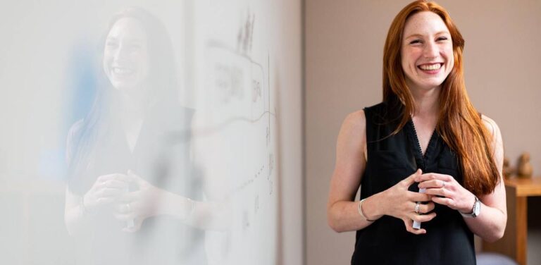 Młoda ruda kobieta przy tablicy. Praca, staż, nauka, studia