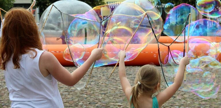 Kobieta i dziewczynka puszczają duże bańki mydlane. Dzieci, zabawa
