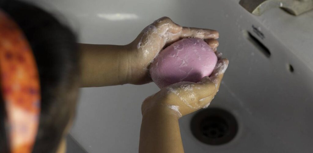 Dziewczynka myje ręce mydłem nad umywalką. Mydło, łazienka, dziecko