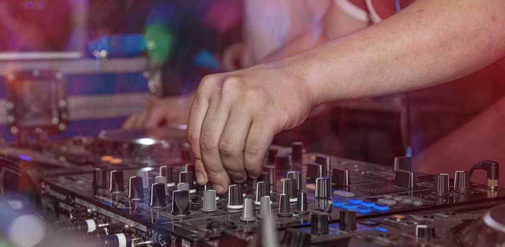 Ręka DJ-a na mikserze konsolety DJ-skiej w klubie. Impreza, klub, muzyka, DJ