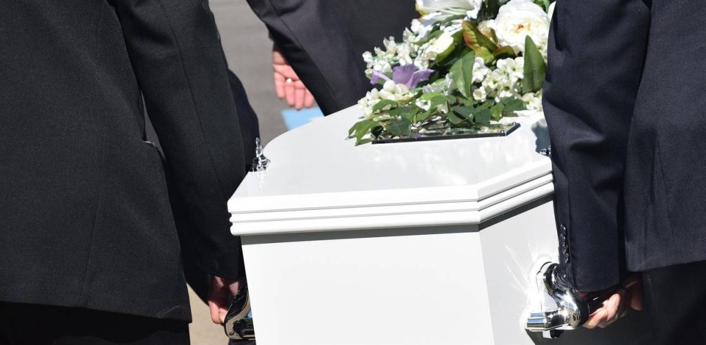 Pogrzeb. Biała trumna niesiona przez mężczyzn w czarnych garniturach