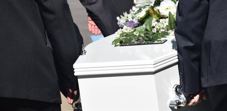 Pogrzeb. Biała trumna niesiona przez mężczyzn w czarnych garniturach