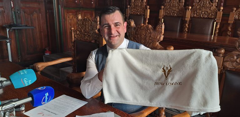 Adam Kopczyński, zastępca burmistrza Chojnic z kocykiem, który otrzymają w wyprawce nowo narodzeni Chojniczanie (fot. Radio Gdańsk/Maria Sowisło)