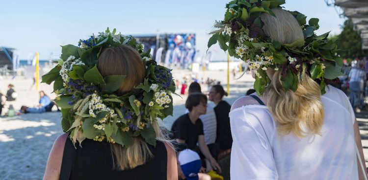 Dwie kobiety z wiankami na głowach spoglądają w stronę plaży podczas Cudawianków