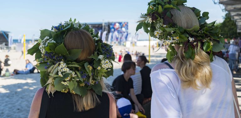 Dwie kobiety z wiankami na głowach spoglądają w stronę plaży podczas Cudawianków