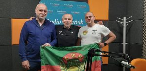 Piotr Klecha, Włodzimierz Machnikowski i Jan Trofimowicz prezentują flagę z logo LZS