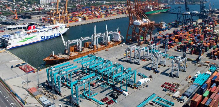 Widok z lotu ptaka na infrastrukturę terminalu w Porcie Gdynia. Po lewej stronie widoczny jest zacumowany prom pasażerski Stena Line oraz statek towarowy, w centrum stoją błękitne suwnice placowe, a po prawej rzędy kolorowych kontenerów i pomarańczowe suwnice nabrzeżowe. Ilustracja rozbudowy Portu Zewnętrznego w modelu Partnerstwa Publiczno-Prywatnego