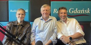 Trzy osoby siedzą obok siebie i uśmiechają się. Na tle widać logo stacji radiowej "Radio Gdańsk". To Aleksandra Kamińska, Marek Haczkowski i Jacek Juncewicz, miłośnicy gry w golfa organizujący pole golfowe w Kwakowie