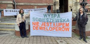 Mieszkańcy Gdańska protestują z transparentem "Wyspa Sobieszewska nie jest łupem deweloperów" przeciwko zabudowie przed budynkiem Rady Miasta Gdańska