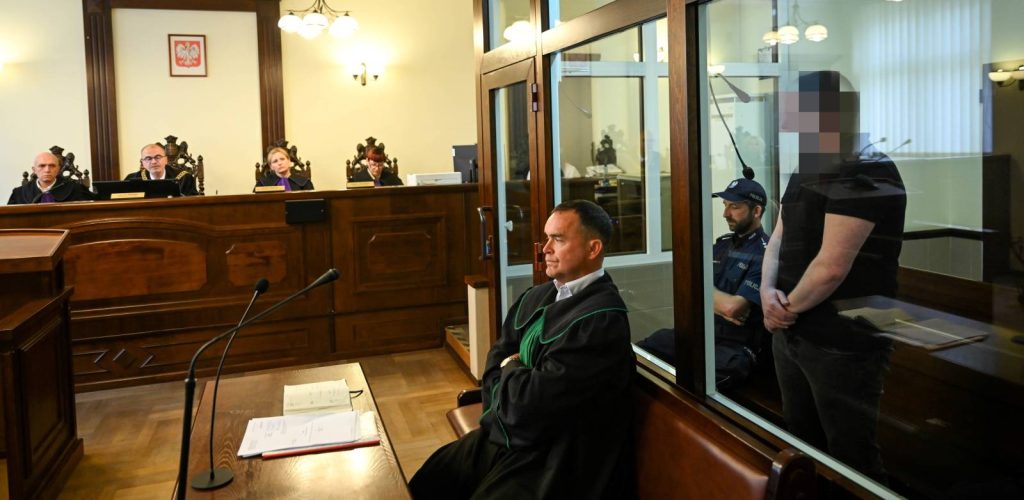 Wnętrze polskiej sali sądowej. Za stołem sędziowskim pod godłem państwowym siedzi skład sędziowski w togach z fioletowymi żabotami. Na pierwszym planie siedzi adwokat w todze z zielonym żabotem, a po prawej stronie – za szklaną szybą zabezpieczającą – stoi oskarżony z rozpikselowaną twarzą w asyście policjanta. To oskarżony Tomasz K. na sali Sądu Apelacyjnego w Gdańsku. Sąd rozpoznaje apelację ws. mężczyzny, oskarżonego o zabójstwo żony i upozorowanie jej śmierci w wypadku oraz sprowadzenie katastrofy w ruchu lądowym w Mezowie na Kaszubach