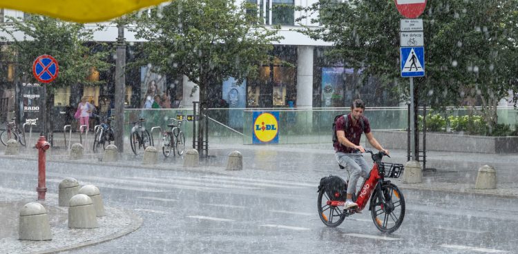 Rowerzystka jedzie ulicą w trakcie ulewnego deszczu