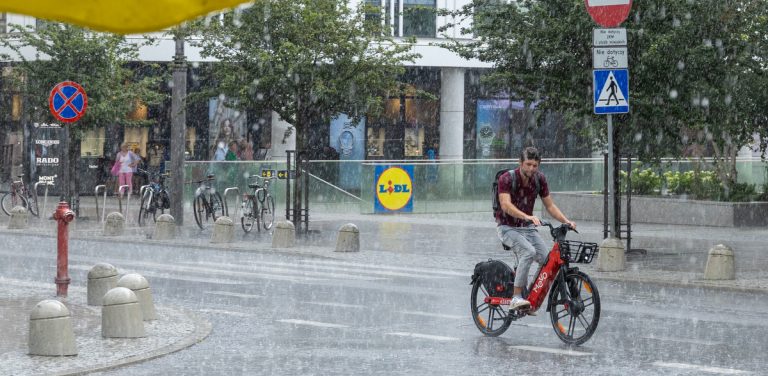 Rowerzystka jedzie ulicą w trakcie ulewnego deszczu