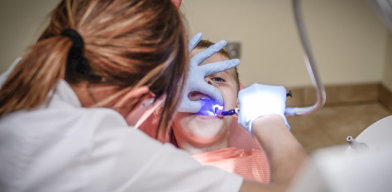 Na zdjęciu dentysta sprawdza uzębienie dziecka