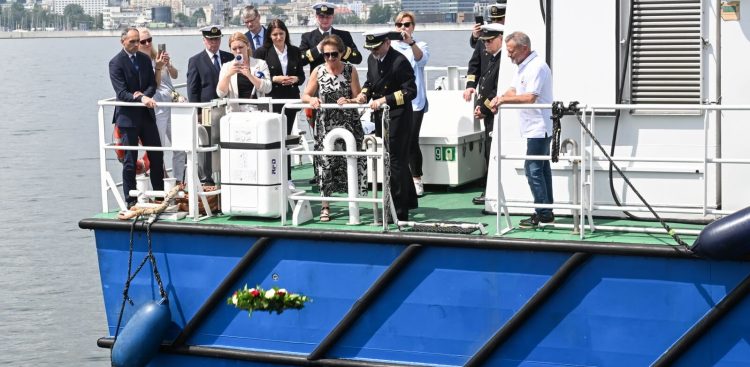 Obecni na statku wrzucają do wody wieńce w hołdzie tym, którzy odeszli na wieczną wachtę