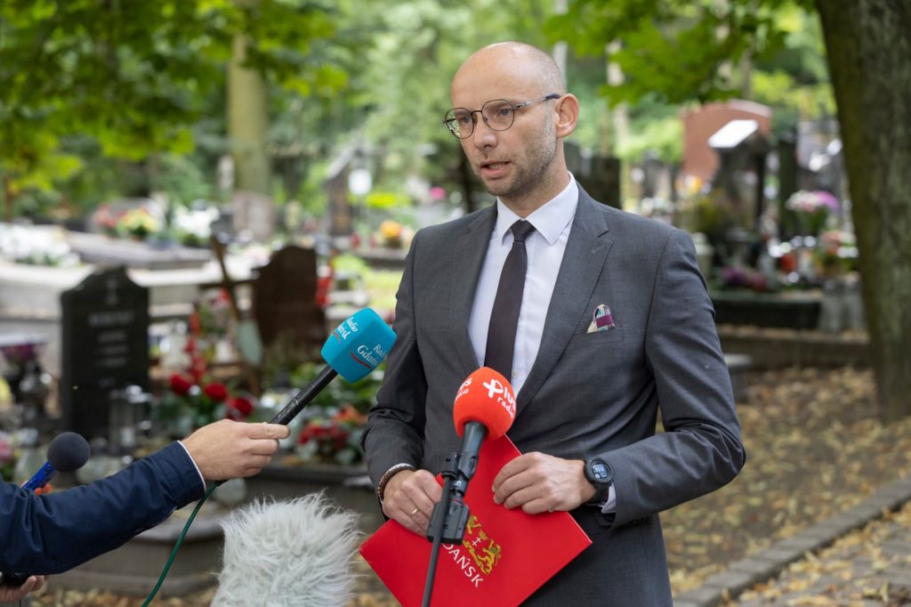 Na tle cmentarza stoi Piotr Kryszewski