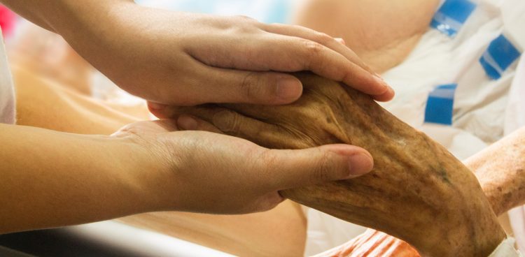 Rodzina trzyma za rękę pacjenta hospicjum