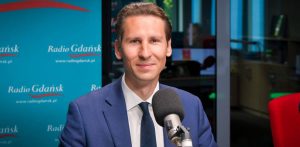 Poseł Kacper Płażyński w garniturze i pod krawatem siedzi przy mikrofonie w studiu Radia Gdańsk