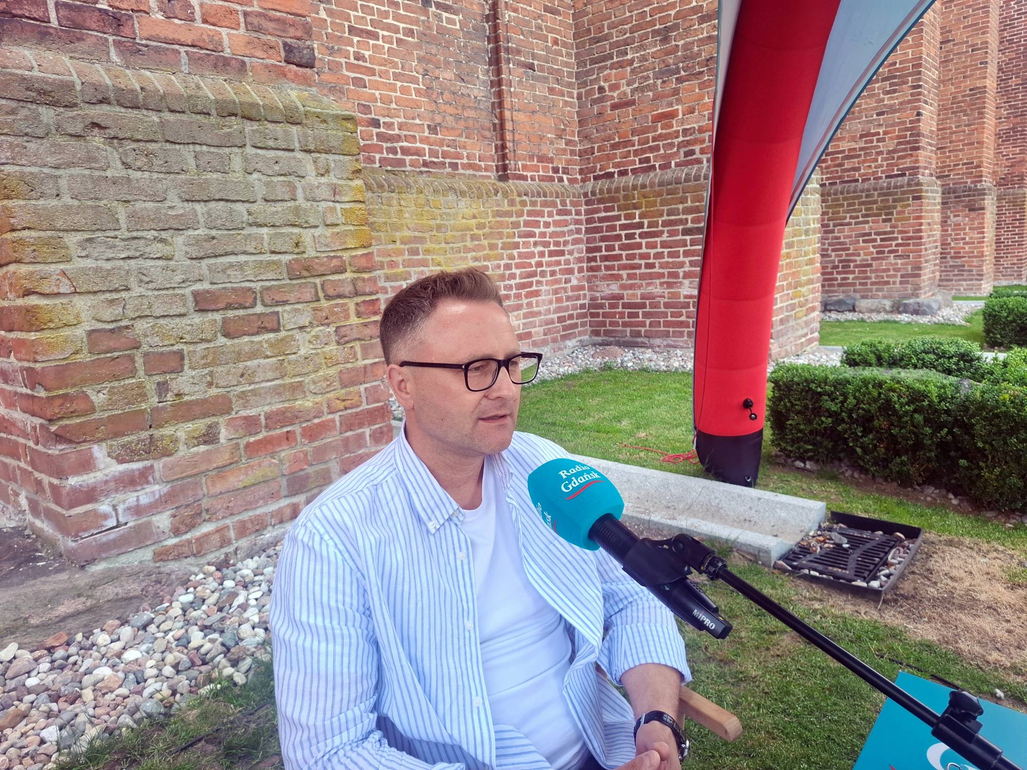 Łukasz Rzepczyński kustosz muzeum zamkowego w Kwidzynie w mobilnym studiu Radia Gdańsk pod murami kwidzyńskiego zamku
