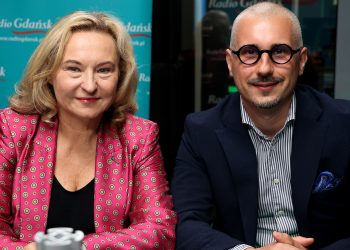 Kobieta o jasnych, blond włosach w różowym żakiecie we wzory oraz mężczyzna w okularach, pasiastej koszuli i ciemnej marynarce. Oboje siedzą uśmiechnięci przy stole w studiu na tle turkusowej ścianki z logo Radia Gdańsk. To Marta Chełkowska i Tomasz Smorgowicz w studiu Radia Gdańsk