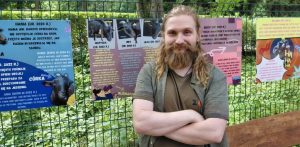 Alan Szydłowski, opiekun z Małego ZOO, uśmiecha się, trzymając na rękach małą świnkę morską na tle powstającej, drewnianej zagrody z kryjówkami