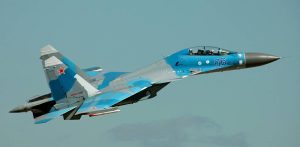 Rosyjski myśliwiec wielozadaniowy Suchoj Su-30 w niebiesko-szarym kamuflażu leci na tle jasnego nieba. Na boku kadłuba widnieje numer 06, a na stateczniku pionowym czerwona gwiazda