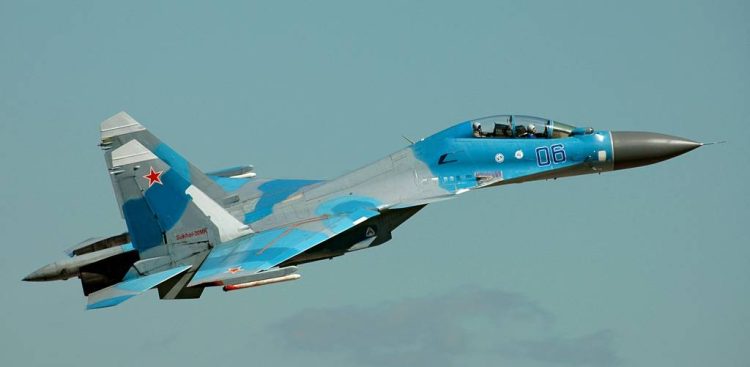 Rosyjski myśliwiec wielozadaniowy Suchoj Su-30 w niebiesko-szarym kamuflażu leci na tle jasnego nieba. Na boku kadłuba widnieje numer 06, a na stateczniku pionowym czerwona gwiazda