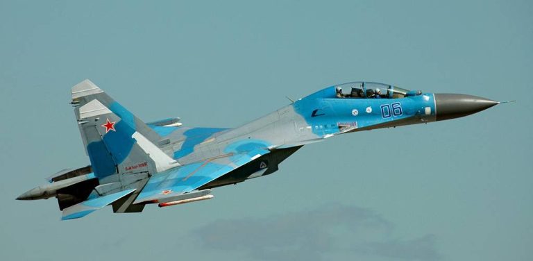 Rosyjski myśliwiec wielozadaniowy Suchoj Su-30 w niebiesko-szarym kamuflażu leci na tle jasnego nieba. Na boku kadłuba widnieje numer 06, a na stateczniku pionowym czerwona gwiazda