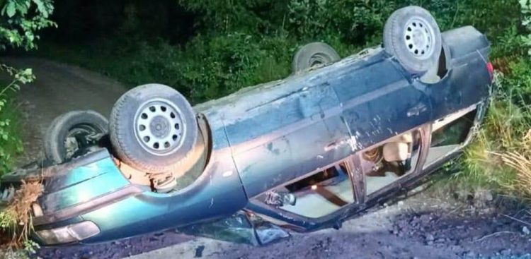Samochód osobowy typu kombi leżący kołami do góry na poboczu nieutwardzonej leśnej drogi po wypadku w Mściszewicach niedaleko Kartuz
