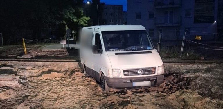 Noc. Biały samochód dostawczy marki Volkswagen unieruchomiony w głębokim błocie i piasku na rozkopanej drodze w Lęborku
