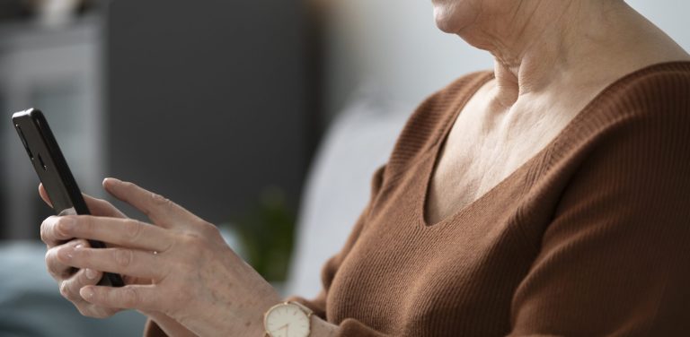 Seniorka trzyma w dłoniach telefon