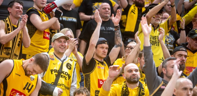 Kibice koszykarskiego klubu Trefl Sopot w żółto-czarnych koszulkach i szalikach klaszczący i dopingujący na trybunach. Nowym zawodnikiem klubu został norweski skrzydłowy Tobias Rotegard
