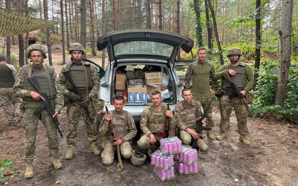 Ukraińscy żołnierze stoją przed samochodem z otrzymaną pomocą humanitarną