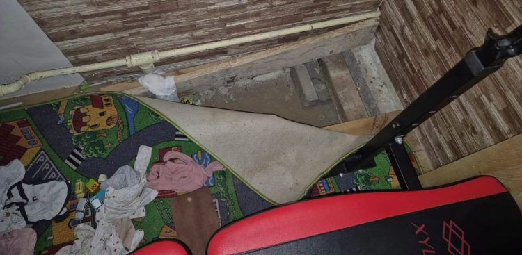 Odwinięty dziecięcy dywanik w motyw uliczek odsłaniający wąski schowek i wykop pod deskami podłogowymi w rogu pokoju, tuż obok ławeczki treningowej. Nietypowa kryjówka pod podłogą i dziecięcym dywanem, w której przed chojnickimi policjantami ukrył się poszukiwany 34-latek