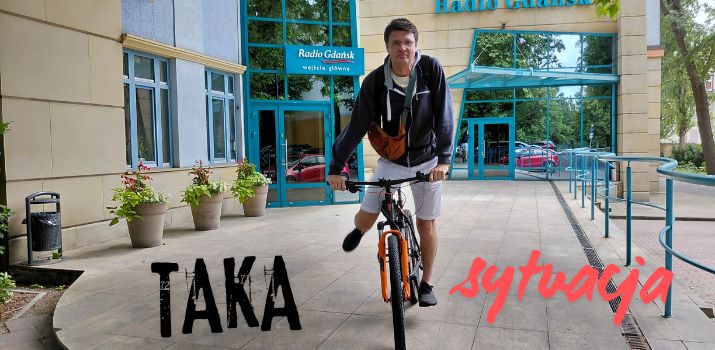 Borys Kossakowski jedzie na rowerze, w tle budynek Radia Gdańsk