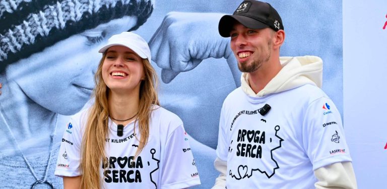Uśmiechnięta kobieta w białej czapce i koszulce z napisem "Droga Serca" oraz stojący obok niej mężczyzna w czarnej czapce z daszkiem i pasującej koszulce, uczestnicy charytatywnego marszu na mecie w Starogardzie Gdańskim