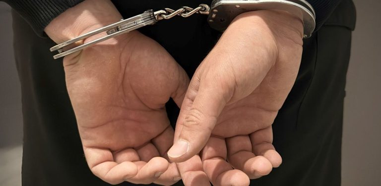 37-latek został zatrzymany za jazdę bez uprawnień, pod wpływem alkoholu, pobicie i obrazę na tle narodowościowym. Na zdjęciu dłonie skute kajdankami