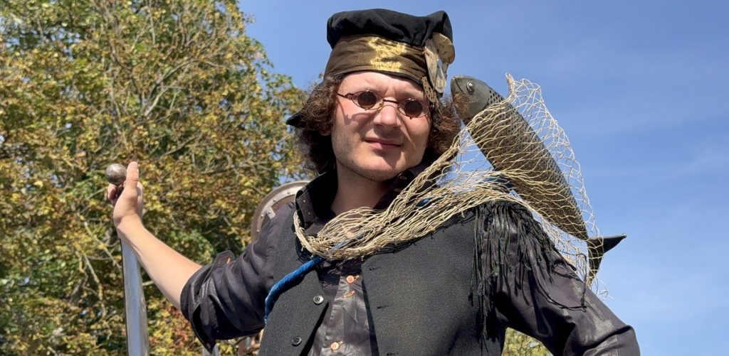 Na zdjęciu osoba w przebraniu ze sztuczną rybą na ramieniu