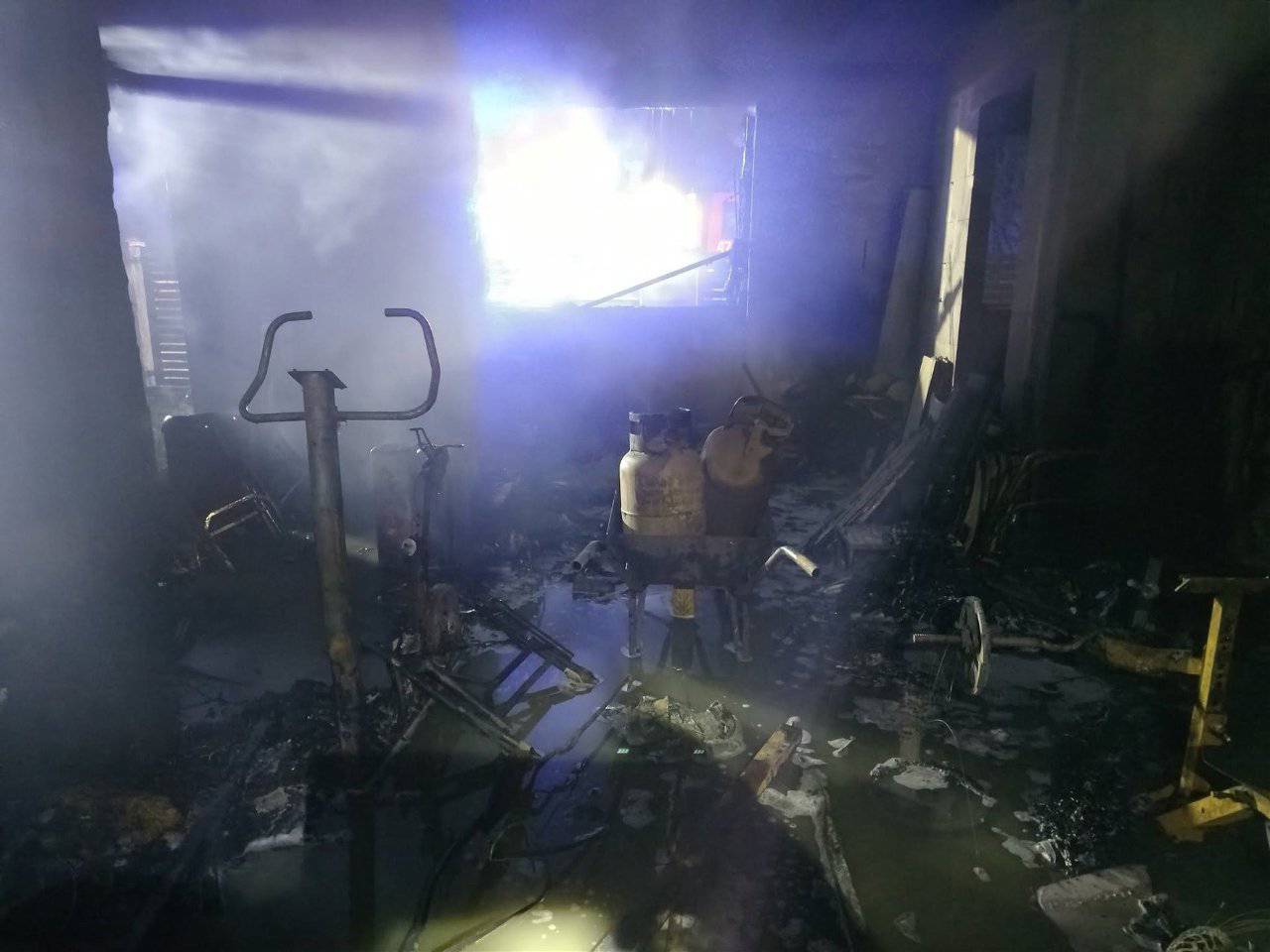 Wnętrze spalonego budynku w Nowęcinie skąpane w dymie, na środku widoczne butle z gazem