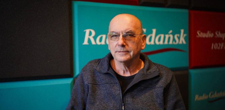 Mężczyzna w okularach i ciemnoniebieskiej rozpinanej bluzie na tle zielono-czerwonych paneli akustycznych z logo Radia Gdańsk w Studio Słupsk. To Witold Polkowski, specjalista prawa pracy, który opowiadał o tym, że pracownicy szpitala w Miastku jak najszybciej powinni złożyć wnioski o wypłatę zaległych wynagrodzeń do Funduszu Gwarantowanych Świadczeń Pracowniczych