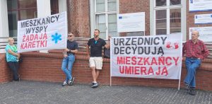 Mieszkańcy wyspy Sobieszewskiej zorganizwoali pikiete. Na plakatach widać napisy "Mieszkańcy wyspy żądają karetki", "Urzędnicy decydują, mieszkańcy umierają"