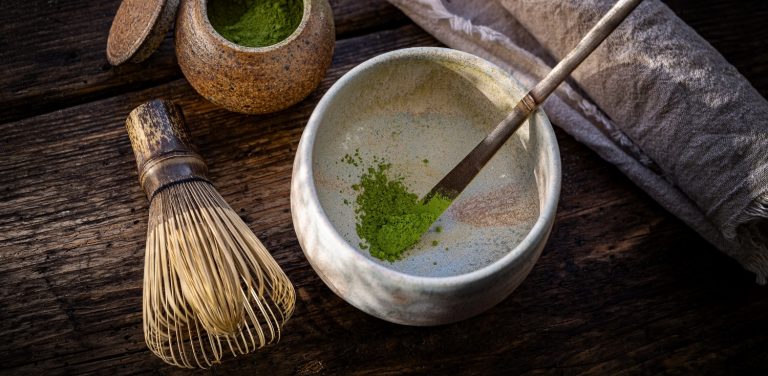 Czym jest matcha? Matcha to tak naprawdę sproszkowana zielona herbata. Powstaje z liści właściwych krzewu kamelii chińskiej. Na zdjęciu kubek matchy i pędzelek.