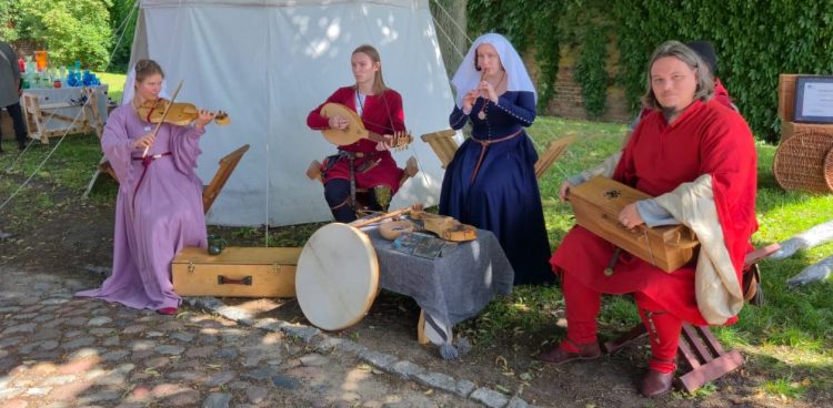 Trzy kobiety i mężczyzna grają na średniowiecznych instrumentach w ramach Oblężenia Malborka