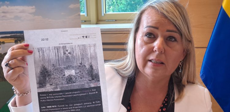 Sekretarz gminy Chojnice Lucyna Zawiszewska prezentuje zdjęcie pierwszego pomnika 18. Pułku Ułanów Pomorskich